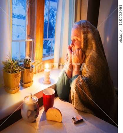 Woman warming herself by a candle in blackout Woman warming herself by a candle in blackout 110658065