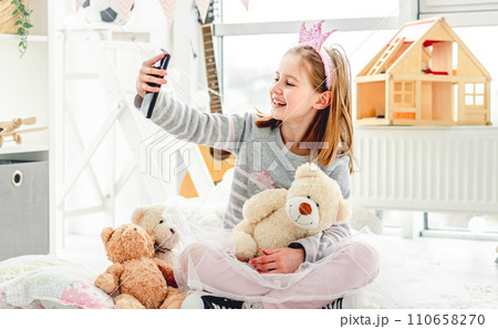 Happy little girl taking photo with toys in cute playroom Happy little girl taking photo with toys in cute playroom 110658270