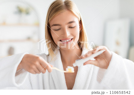 blonde lady practices dental care using toothpaste and toothbrush indoor blonde lady practices dental care using toothpaste and toothbrush indoor 110658542