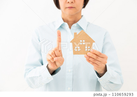 戸建ての住宅模型を持って人差し指を立てるミドル女性 110659293