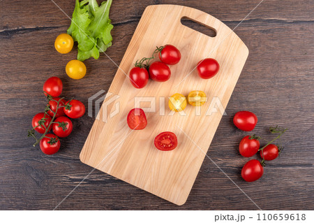 Top view of whole and cut tomatoes on a cutting board. 110659618
