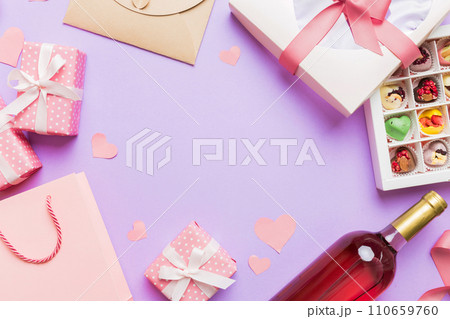top view photo of st valentine day decor shopping, bag, wine, bottle, envelope, gift, box, candy and red heart on colored background with empty space. Frame background top view photo of st valentine day decor shopping, bag, wine, bottle, envelope, gift, box, candy and red heart on colored background with empty space. Frame background 110659760