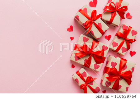 Top view photo of valentine day decorations gift box with red ribbon bow on colored background. Holiday gift boxes with top view Top view photo of valentine day decorations gift box with red ribbon bow on colored background. Holiday gift boxes with top view 110659764
