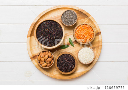 Various superfoods in smal bowl on colored background. Superfood as rice, chia, quinoa, lentils, nuts, sesame seeds, almonds. top view Various superfoods in smal bowl on colored background. Superfood as rice, chia, quinoa, lentils, nuts, sesame seeds, almonds. top view 110659773