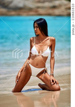 Sexy girl in white bikini posing at the tropical beach at sunny day 110661610