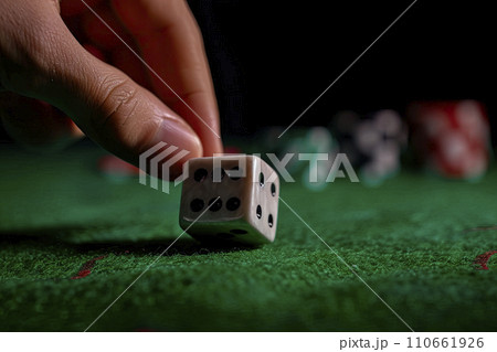 Close up of male hand rolling the dice on green poker table with black background 110661926