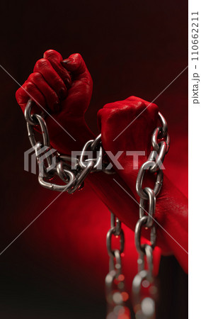 bloodied hands clenched into fists in the shackles of a metal chain symbolize slavery, protest and the struggle for freedom 110662211