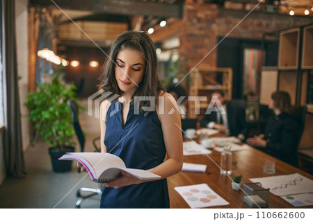 Focused student girl studying in public library for work on study research project, holding learning papers, notebook. 110662600