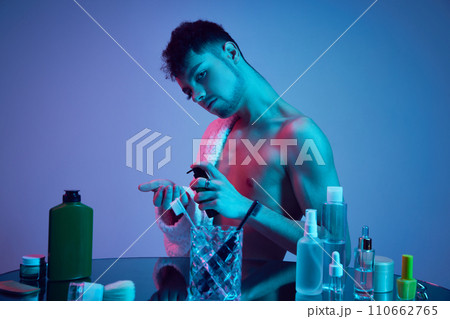 Glamour unveiled. Male face captivates with his dual nature in neon-lit bathroom. Immerse yourself in world of cosmetic indulgence and self-care rituals. 110662765