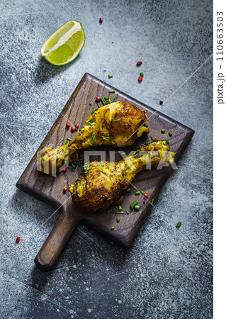Two chicken drumsticks on a wooden board Two chicken drumsticks on a wooden board 110663503