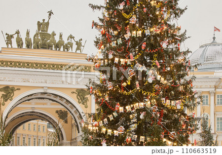 The main Christmas tree shimmers with lights of decorations, the central Palace square of the city decorated for the celebration during the snowfall, Arch of the General Staff, flag of Armed Forces The main Christmas tree shimmers with lights of decorations, the central Palace square of the city decorated for the celebration during the snowfall, Arch of the General Staff, flag of Armed Forces 110663519