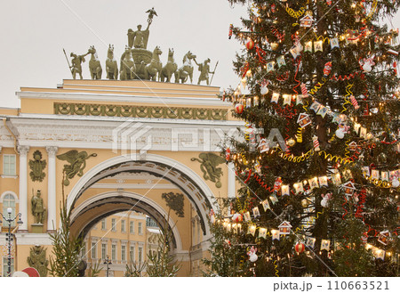 The main Christmas tree shimmers with lights of decorations, the central Palace square of the city decorated for the celebration during the snowfall, Arch of the General Staff, flag of Armed Forces The main Christmas tree shimmers with lights of decorations, the central Palace square of the city decorated for the celebration during the snowfall, Arch of the General Staff, flag of Armed Forces 110663521