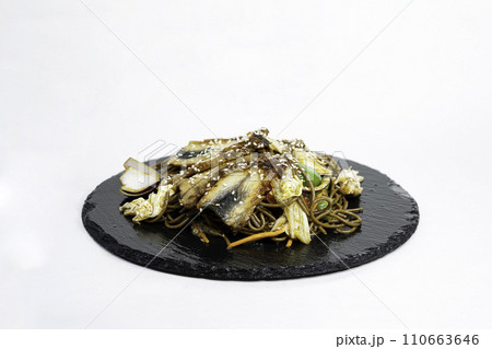 fried noodles with vegetables and meat in a flat plate on a white background, side view 110663646