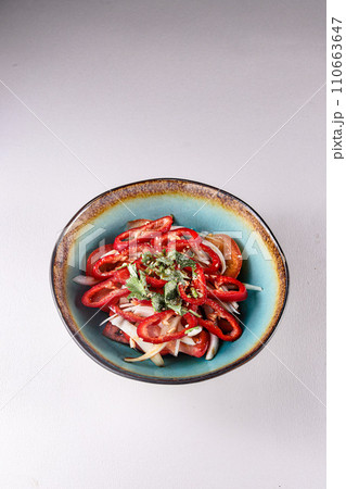 red sweet pepper with onions, tomatoes and vegetables in a plate on a white background, top view 110663647