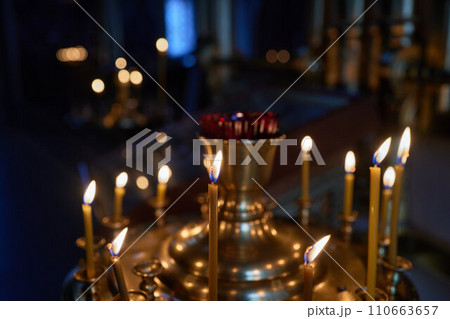 Burning church candles in a gilded candlestick in a temple in the dark Burning church candles in a gilded candlestick in a temple in the dark 110663657
