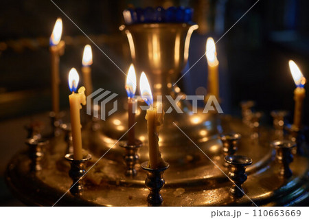 Burning church candles in a gilded candlestick in a temple in the dark 110663669