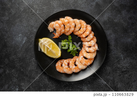 Cooked shrimps in a black plate, over dark background 110663829