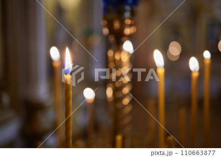 Burning church candles in a gilded candlestick in a temple in the dark Burning church candles in a gilded candlestick in a temple in the dark 110663877