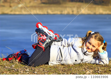 young girl in roller skates lays on the ground 110663906
