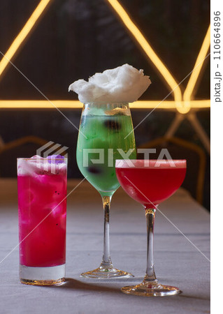Summer cocktail with fruit and ice. Drink on white table over pink wall in sunlight with palm leaf shadow. Summer, tropical, fresh cocktail concept. 110664896