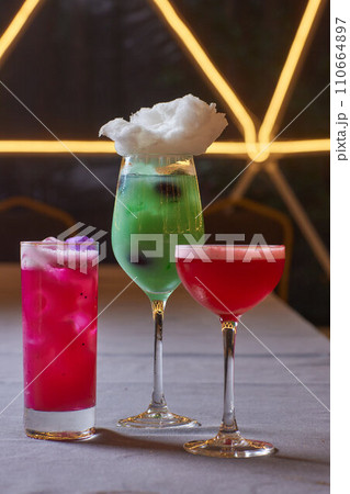 Summer cocktail with fruit and ice. Drink on white table over pink wall in sunlight with palm leaf shadow. Summer, tropical, fresh cocktail concept. 110664897