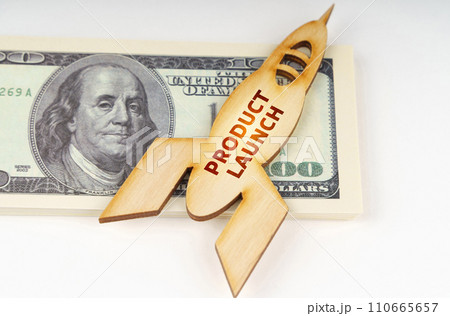 On the dollars lies a wooden model of a rocket with the inscription - Product Launch On the dollars lies a wooden model of a rocket with the inscription - Product Launch 110665657