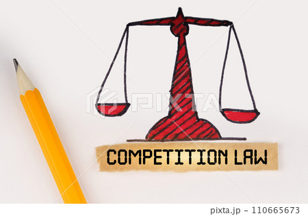 Next to the painted scales of justice lies a pencil and a strip of paper with the inscription - Competition Law Next to the painted scales of justice lies a pencil and a strip of paper with the inscription - Competition Law 110665673