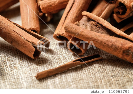 Closeup detail macro - Heap of cinnamon bark sticks on linen tablecloth. Closeup detail macro - Heap of cinnamon bark sticks on linen tablecloth. 110665793