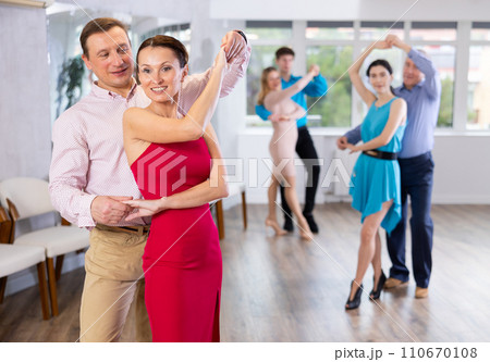 Group of different ages active people in festive clothes dancing dance movements in studio Group of different ages active people in festive clothes dancing dance movements in studio 110670108
