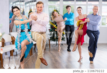 Cheerful man dancing jive with young brunette during corporate Christmas party 110670222