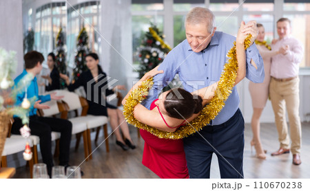 Christmas and New Year holiday - couples dancing with tinsel near Christmas tree Christmas and New Year holiday - couples dancing with tinsel near Christmas tree 110670238