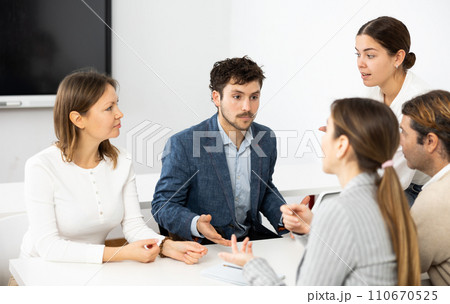 Colleagues sharing ideas and points of view, listening to each other while sitting around desk after advanced training course 110670525
