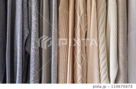 Hanger with neutral beige and white clothes on a white background. 110670878