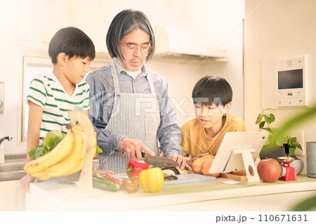 タブレットを見ながら料理をする父親と息子 110671631