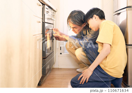 オーブンの中をのぞく父親と息子 110671634