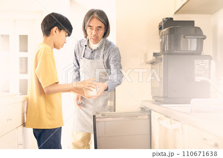食洗機から食器を取り出す父親と手伝う男の子 110671638