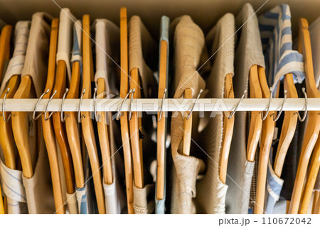 Hanger with beautiful neutral beige, white and gray clothes on a white background. View from above. 110672042