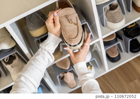 Female hands choosing boots shoe cupboard comfortable storage organize closeup top view Female hands choosing boots shoe cupboard comfortable storage organize closeup top view 110672052