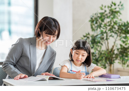 学習塾で勉強する小学生と講師。 学習塾で勉強する小学生と講師。 110673475