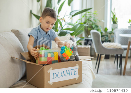 Boy child puts toys in a cardboard box for charity. Donation concept. Boy child puts toys in a cardboard box for charity. Donation concept. 110674459