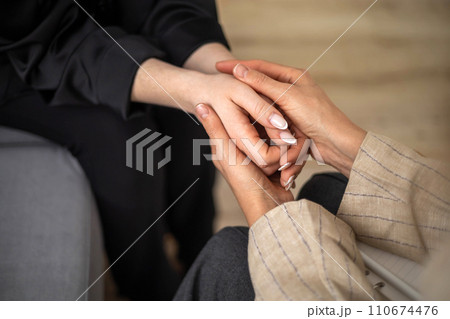 Two woman holding hands concept of support sisterhood care unity and togetherness closeup top view 110674476