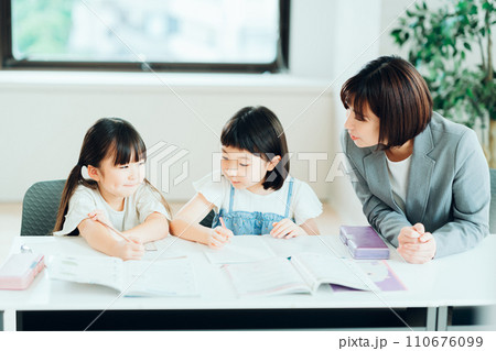 学習塾で勉強をする小学生と講師。 学習塾で勉強をする小学生と講師。 110676099