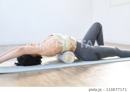 フォームローラーを使って背中の筋膜リリースをする女性 フォームローラーを使って背中の筋膜リリースをする女性 110677171