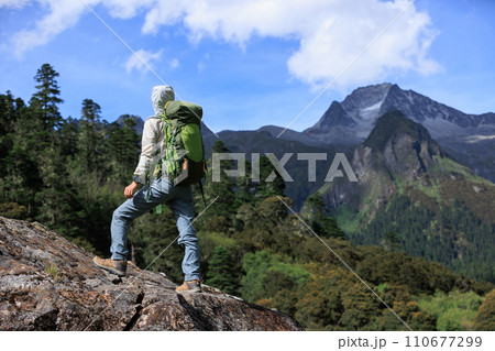 Woman hiker climbing to mountain top in tibet Woman hiker climbing to mountain top in tibet 110677299