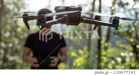 People remote control a flying drone in summer forest People remote control a flying drone in summer forest 110677341