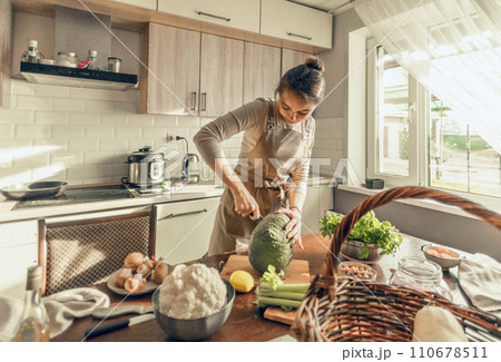 A young woman cuts a pumpkin with a knife in the kitchen. The concept of healthy nutrition A young woman cuts a pumpkin with a knife in the kitchen. The concept of healthy nutrition 110678511
