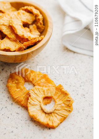 Dried pineapple rings on kitchen table. 110679209