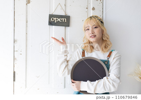 開店準備　扉の前に立つ若い女性 110679846