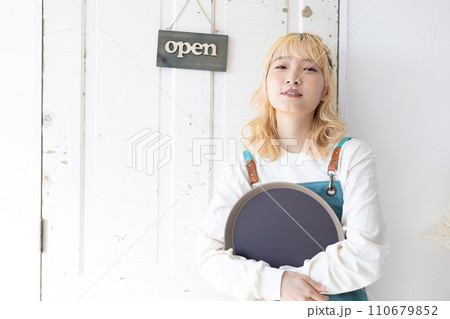 開店準備　扉の前に立つ若い女性 110679852
