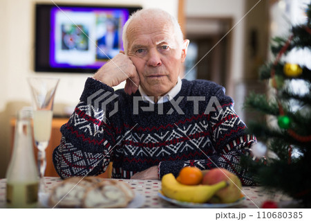 Portrait of tired lonely elderly man at the dinner table during christmas celebration 110680385